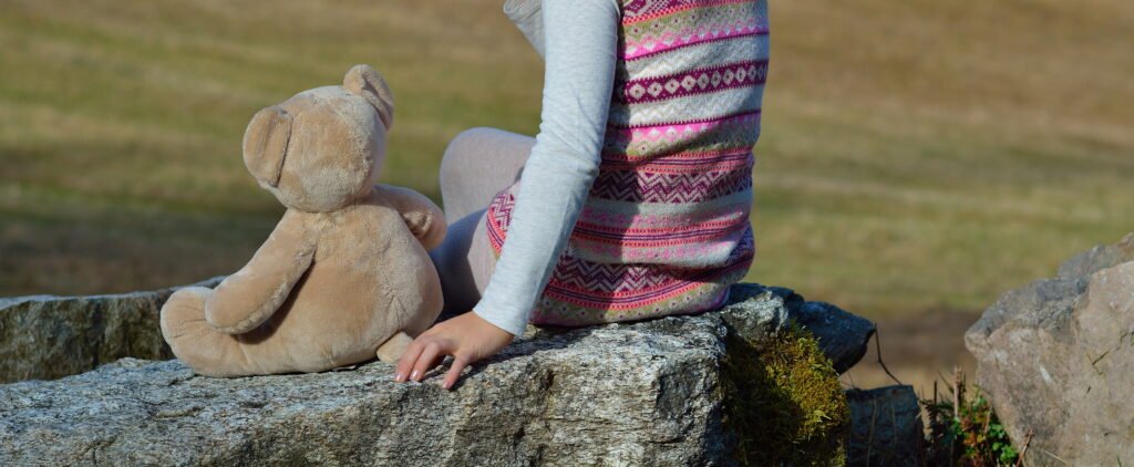 Bienfaits des peluches : une personne assise à côté d'une peluche dans la nature