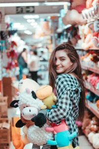 Adultes qui collectionnent des peluches : une femme dans un magasin avec des peluches dans les bras