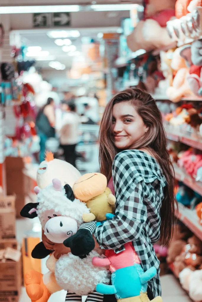 Adultes qui collectionnent des peluches : une femme dans un magasin avec des peluches dans les bras