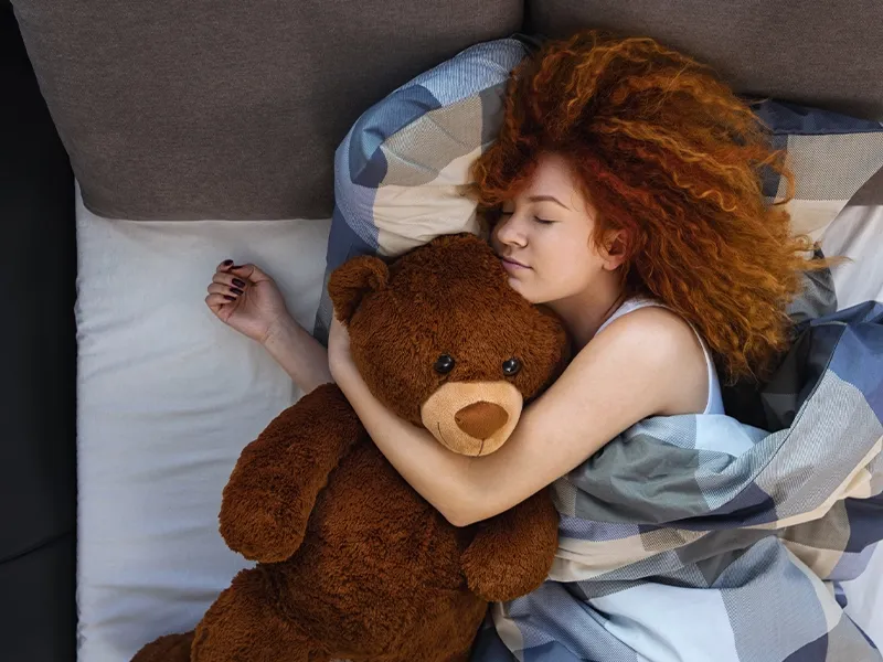 Dormir avec une peluche à 40 ans : femme endormie avec sa peluche