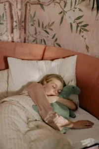 Calmer l’anxiété : une femme dort profondément avec sa peluche de dinosaure