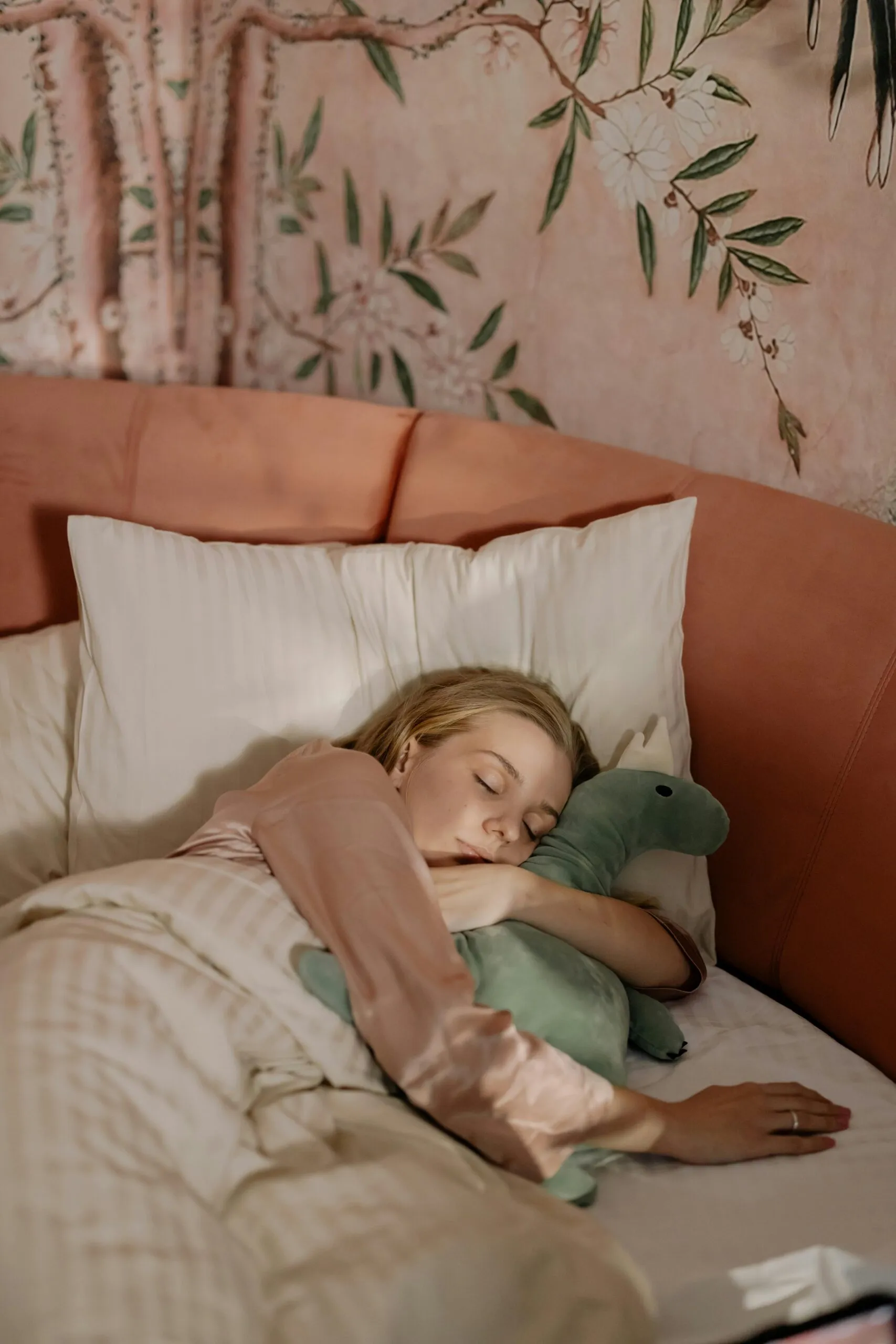 Calmer l’anxiété : une femme dort profondément avec sa peluche de dinosaure